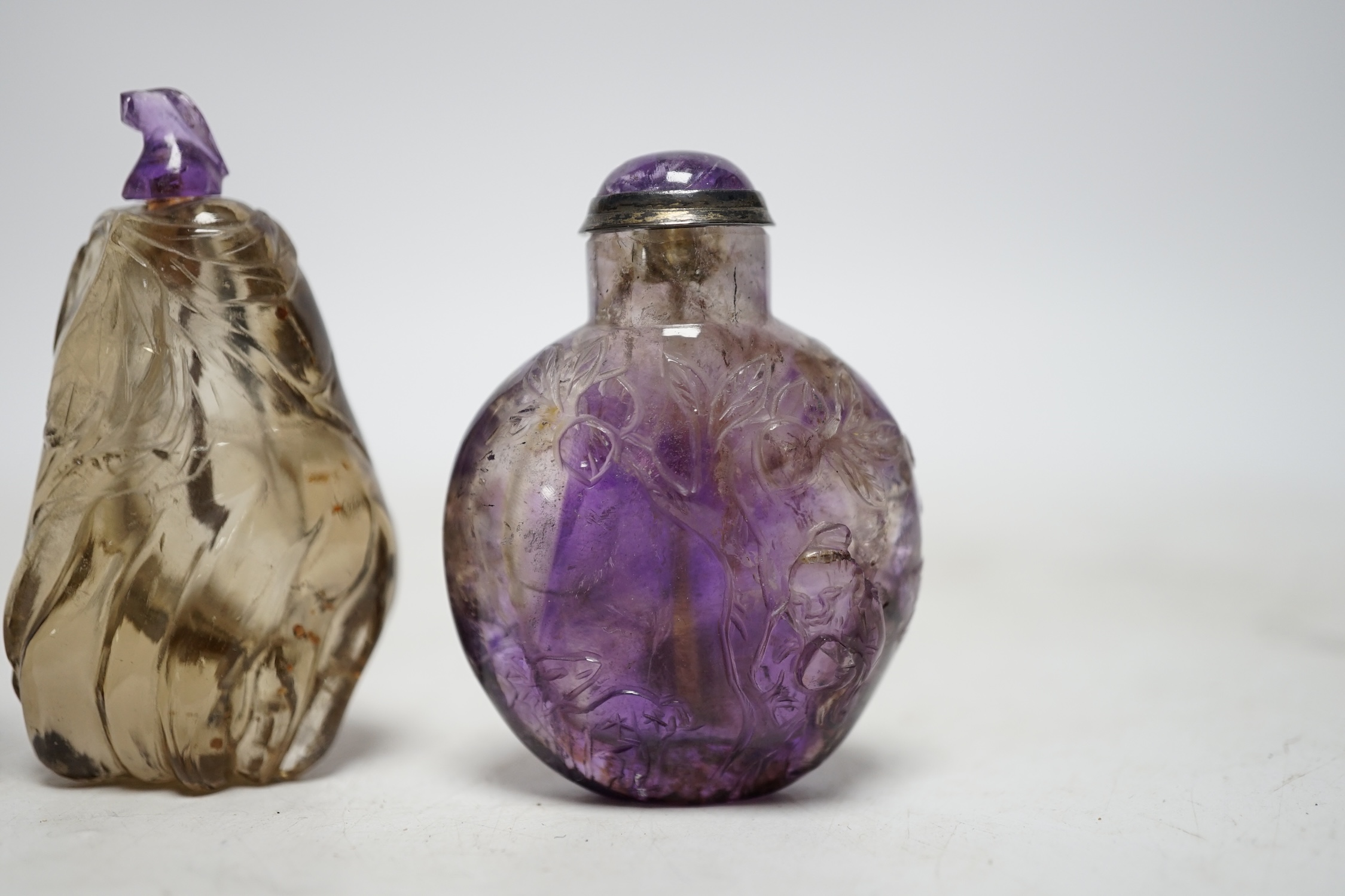 Three Chinese carved quartz snuff bottles, 19th/20th century to include a smoky quartz shuangxi bottle, an amethyst quartz bottle and a small smoky quartz gourd shaped bottle, largest 6.5cm high